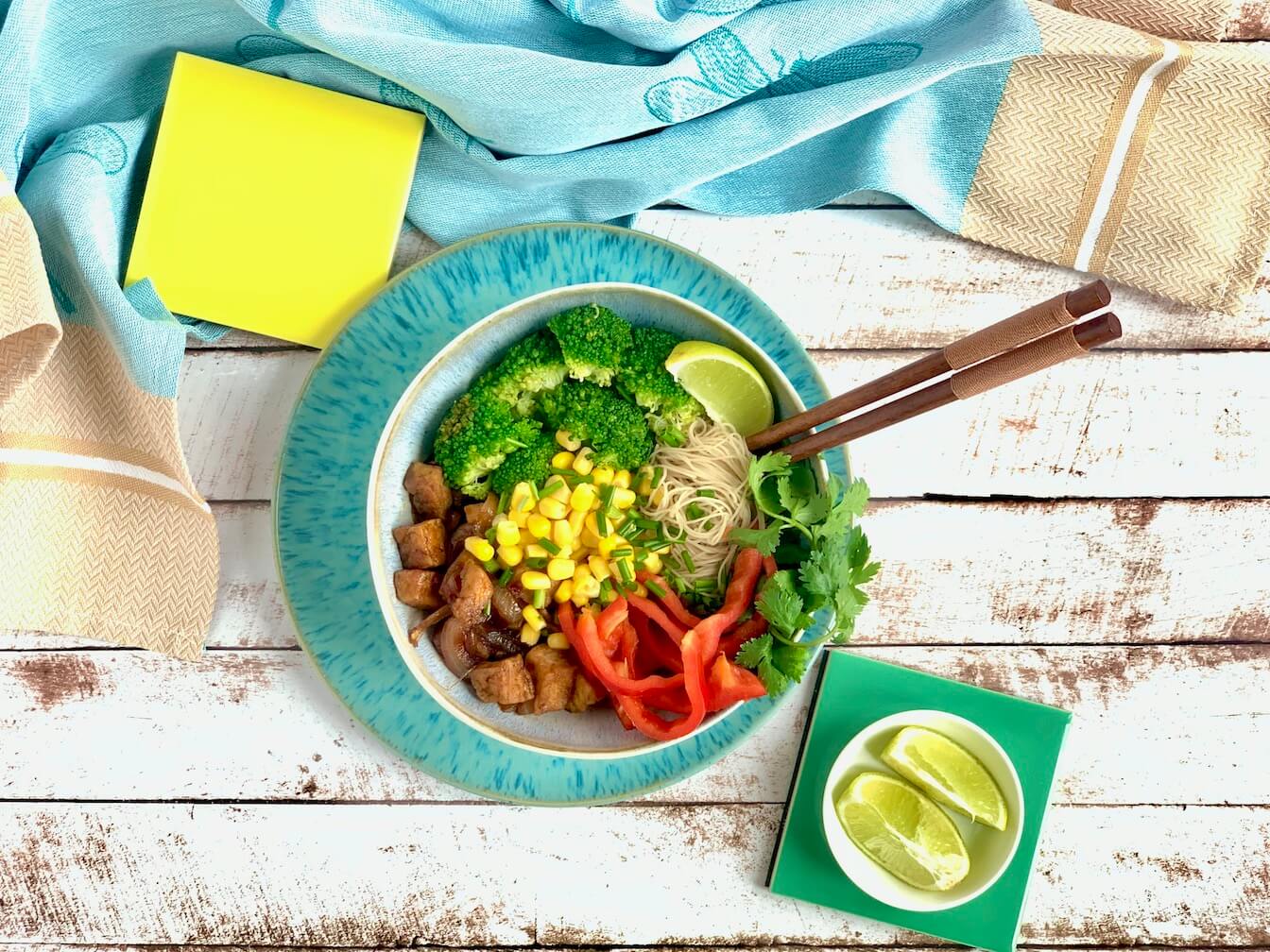 vegan buddha bowl with rice noodles, broccoli, tofu, paprika, lime, corn, cilantro
